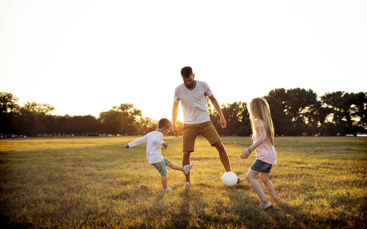 Dad playing soccer with children